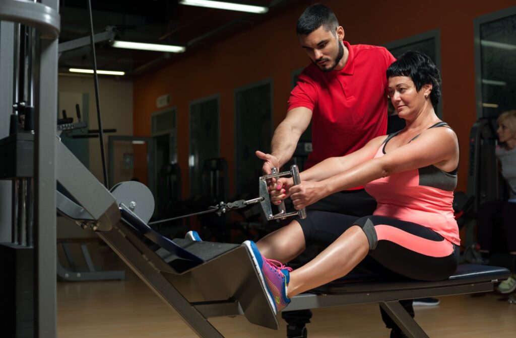 A woman working with a personal trainer at a gym