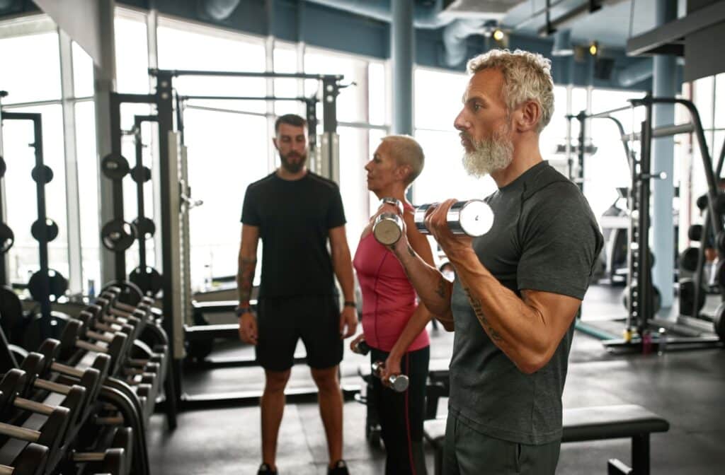 Two adults working with a personal training during resistance training