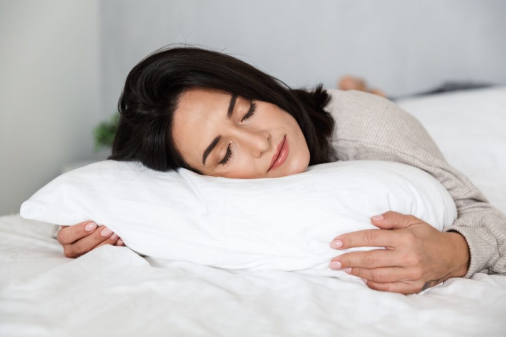 Woman sleeping peacefully on white pillow in comfortable bed.